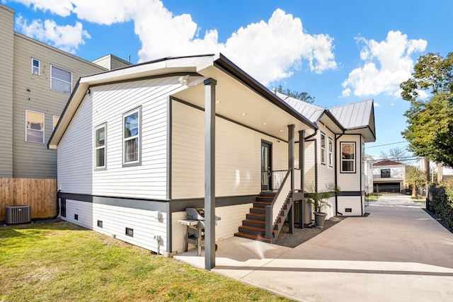 view of home's exterior featuring a patio, metal roof, fence, cooling unit, and a yard