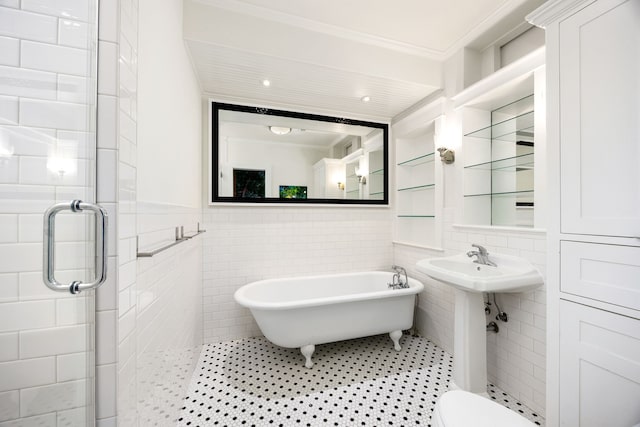 bathroom with toilet, tile walls, ornamental molding, a soaking tub, and tile patterned floors