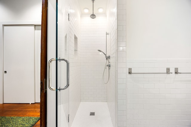 full bathroom with a stall shower, tile walls, and wood finished floors