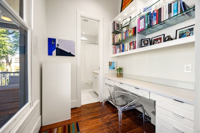 office area with dark wood-style flooring and built in desk