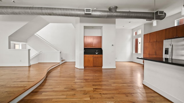 kitchen featuring a high ceiling, stainless steel fridge with ice dispenser, light hardwood / wood-style floors, and pendant lighting