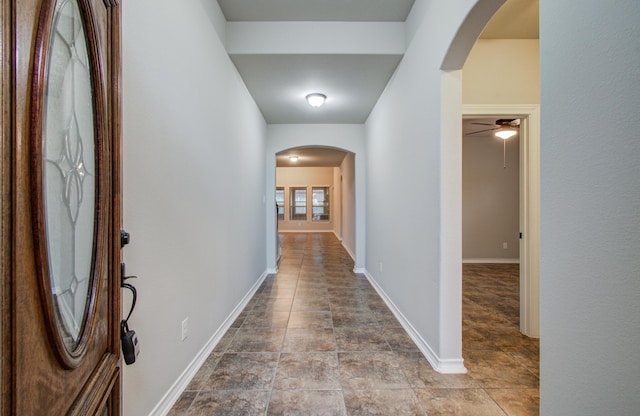 corridor with arched walkways and baseboards