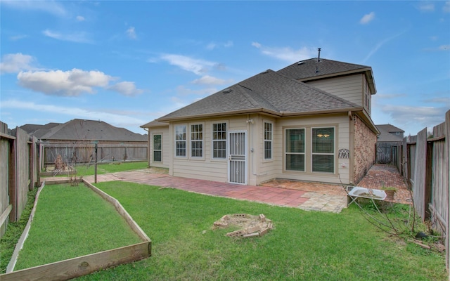 back of property with a shingled roof, a lawn, a patio area, and a fenced backyard