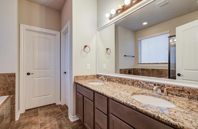 bathroom with tiled tub, visible vents, a sink, and double vanity