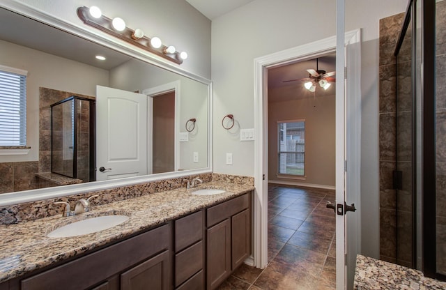 full bath with ceiling fan, double vanity, a stall shower, and a sink