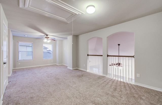 empty room with a ceiling fan, carpet, attic access, and baseboards