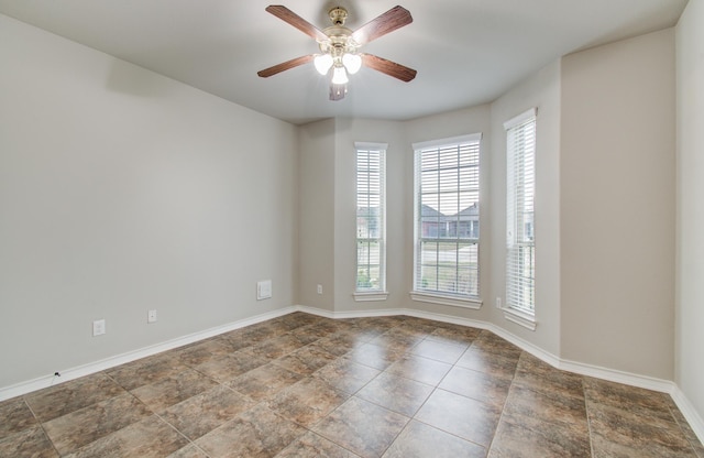 empty room featuring a ceiling fan and baseboards