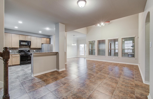 kitchen with range with gas stovetop, open floor plan, freestanding refrigerator, light countertops, and black microwave