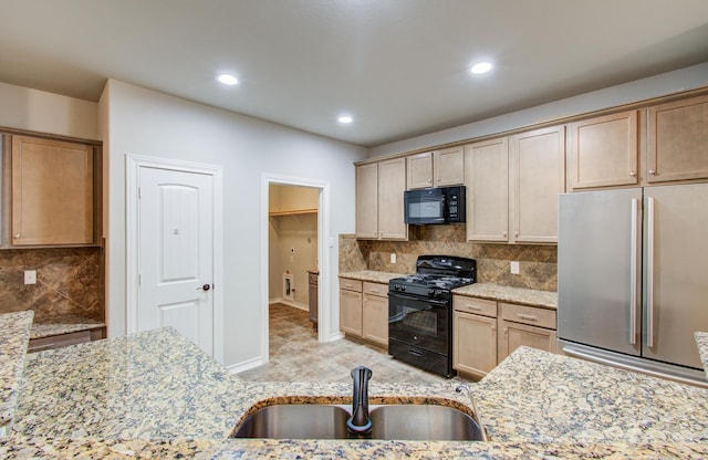 kitchen featuring decorative backsplash, a sink, black appliances, and light stone countertops