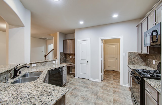 kitchen featuring light stone counters, a sink, baseboards, black appliances, and tasteful backsplash