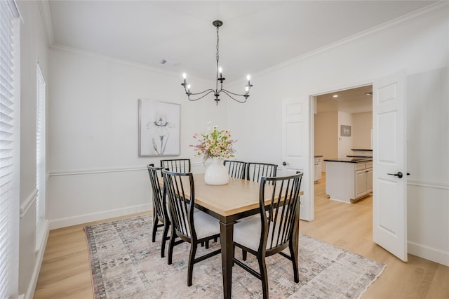 dining space featuring light hardwood / wood-style floors, an inviting chandelier, and ornamental molding