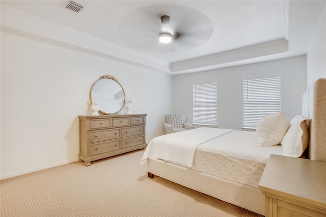 carpeted bedroom with a tray ceiling and ceiling fan