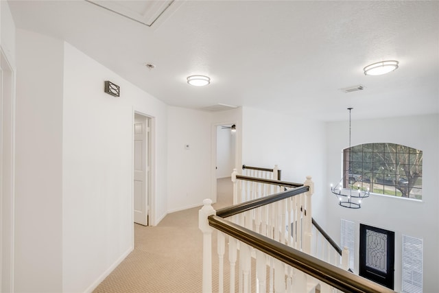 hallway featuring light carpet and a chandelier