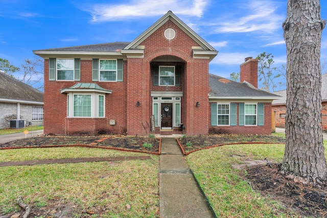 traditional home featuring brick siding, a chimney, a front lawn, and central air condition unit