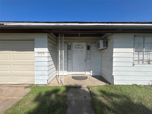 entrance to property featuring a garage and a wall mounted air conditioner