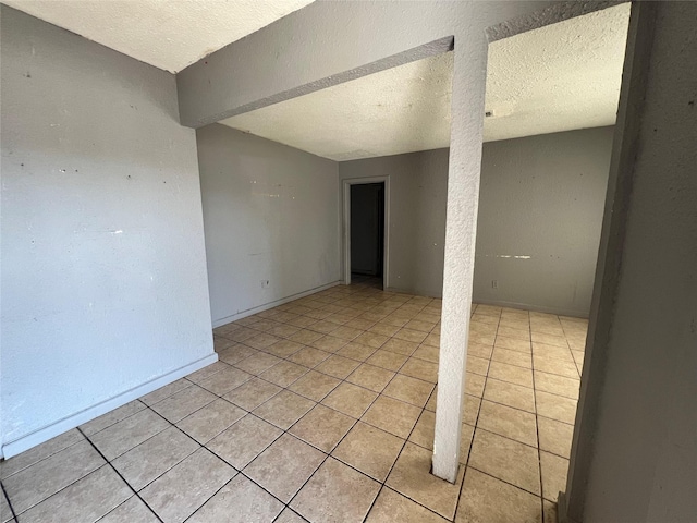 spare room with a textured ceiling and light tile patterned floors