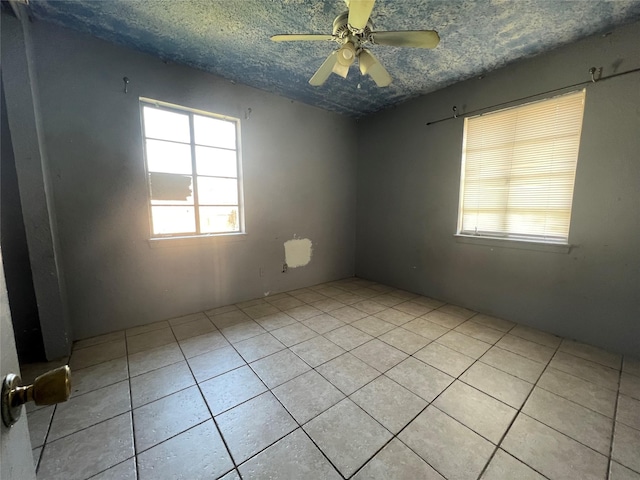 unfurnished room featuring a textured ceiling, ceiling fan, and light tile patterned floors