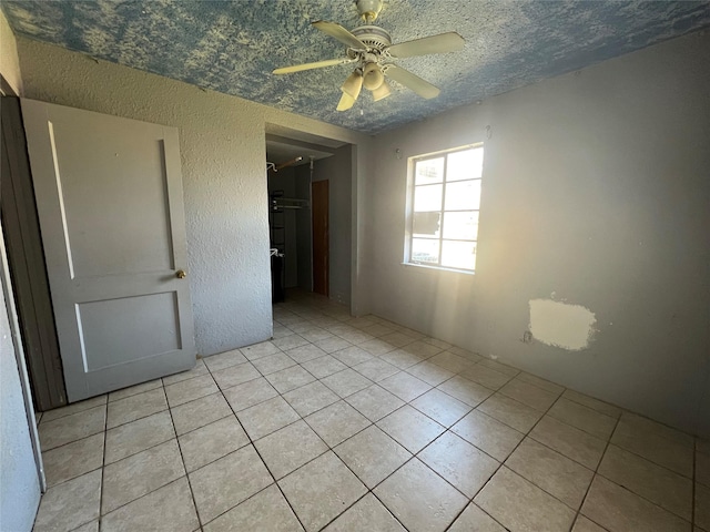 unfurnished room with light tile patterned flooring, ceiling fan, and a textured ceiling