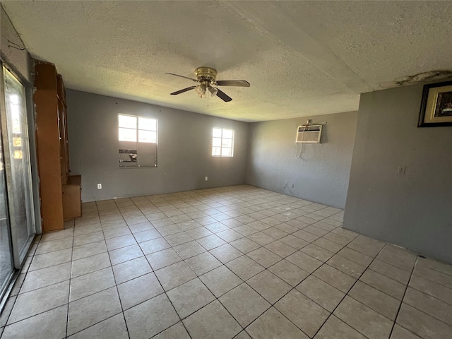 spare room with a wall unit AC, ceiling fan, light tile patterned flooring, and a textured ceiling