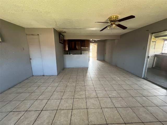 unfurnished living room featuring ceiling fan, light tile patterned floors, and a textured ceiling