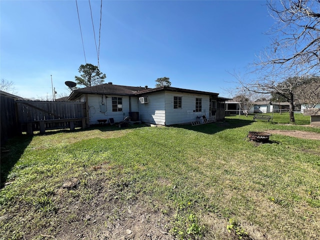 rear view of property featuring an outdoor fire pit and a lawn