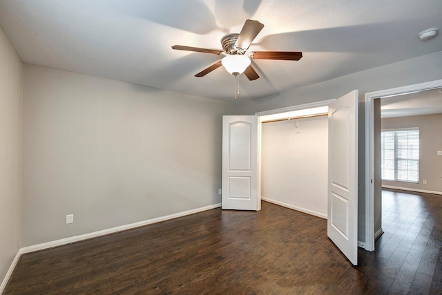 unfurnished bedroom with dark wood-style floors, ceiling fan, a closet, and baseboards