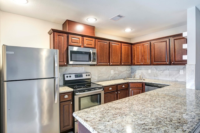 kitchen with light stone counters, stainless steel appliances, a sink, visible vents, and tasteful backsplash