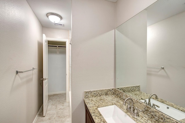 full bath with a spacious closet, vanity, visible vents, and baseboards