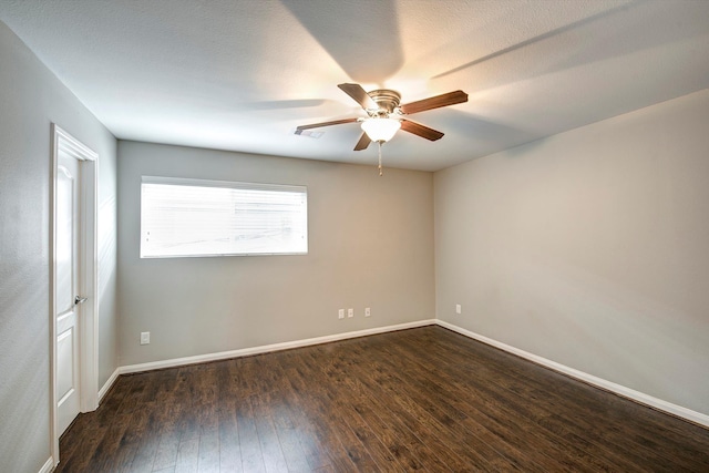 empty room featuring dark wood-type flooring, ceiling fan, and baseboards