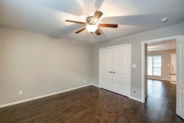 unfurnished bedroom with a ceiling fan, a closet, baseboards, and dark wood-style flooring