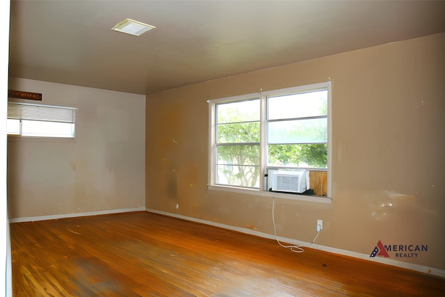 unfurnished room with cooling unit and hardwood / wood-style floors