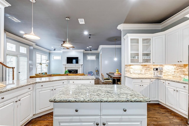 kitchen featuring ceiling fan, white cabinets, hanging light fixtures, ornamental molding, and tasteful backsplash