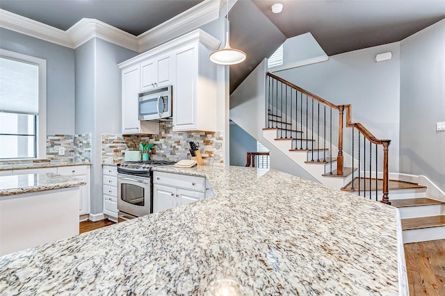 kitchen with white cabinetry, light stone countertops, stainless steel appliances, and wood-type flooring