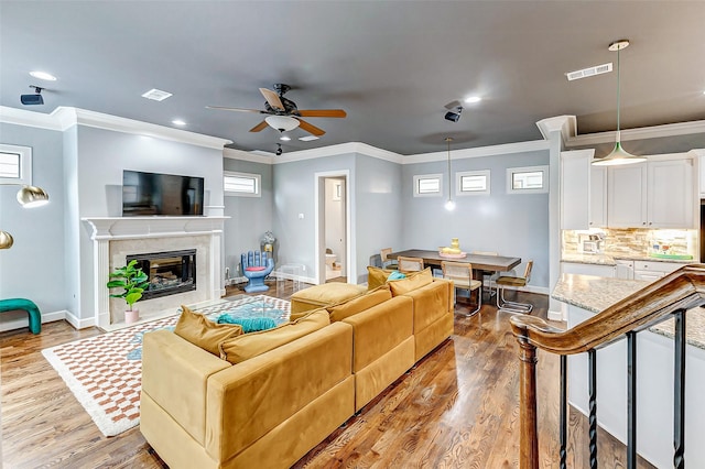 living room featuring ceiling fan, crown molding, light hardwood / wood-style floors, and a premium fireplace