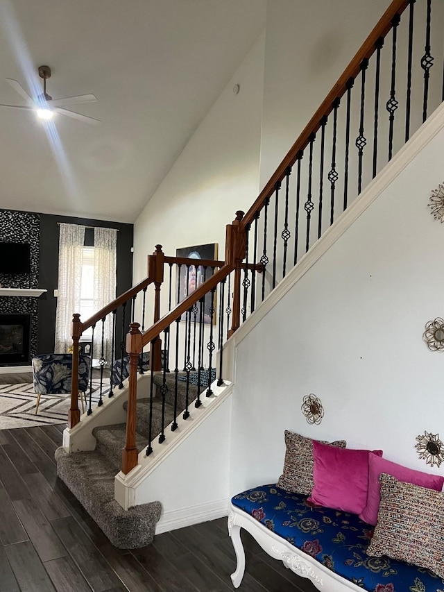 staircase featuring a tile fireplace, hardwood / wood-style flooring, and vaulted ceiling