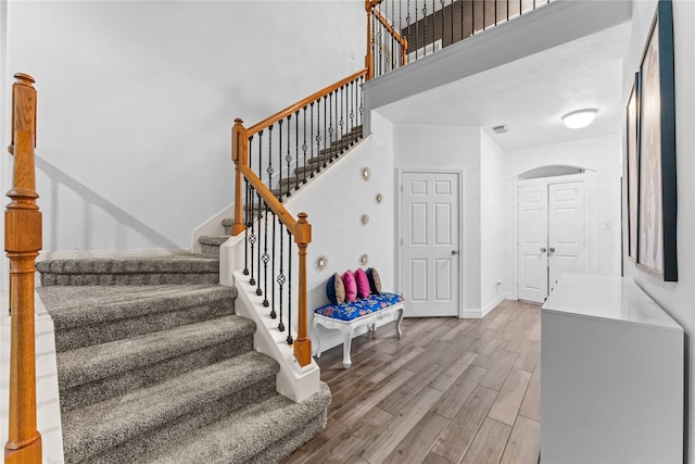 stairway with wood finished floors, visible vents, and baseboards