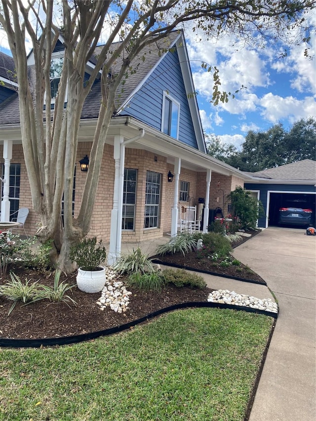 exterior space with a porch, brick siding, and a garage