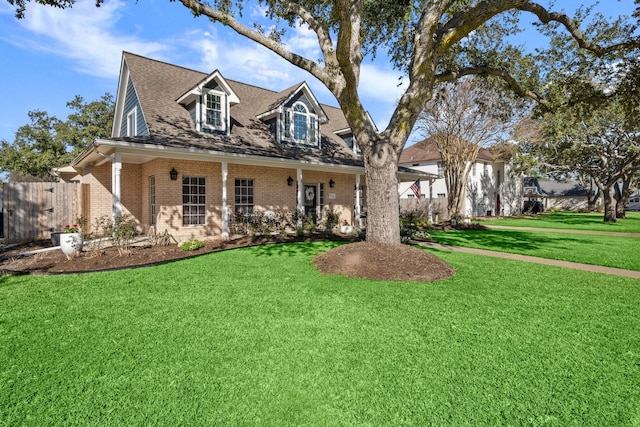 view of front facade featuring brick siding, fence, a front lawn, and roof with shingles