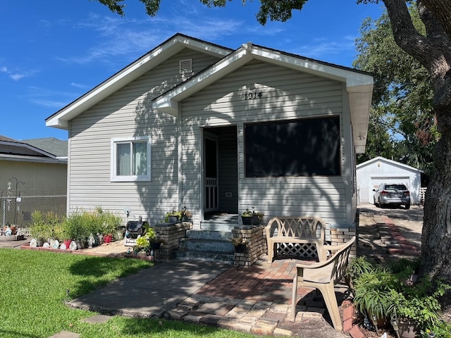 view of front of home featuring a garage, a patio area, a front lawn, and an outdoor structure