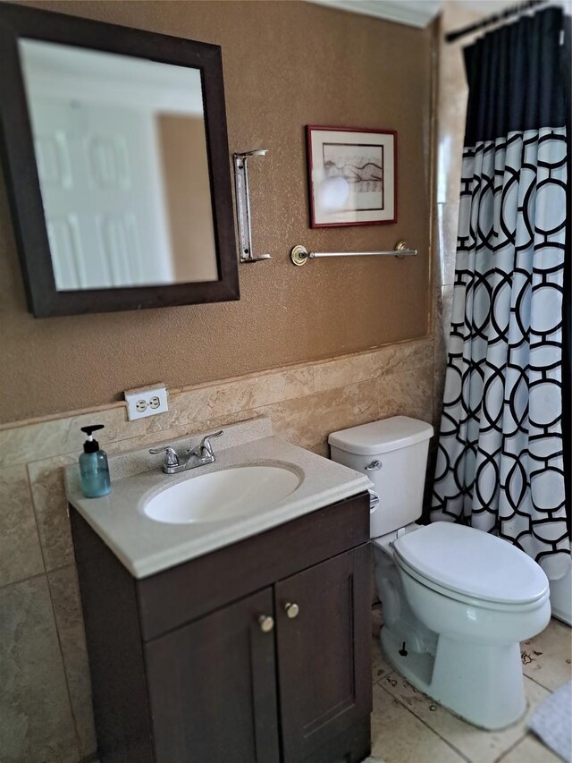 bathroom featuring tile walls, vanity, tile patterned flooring, and toilet