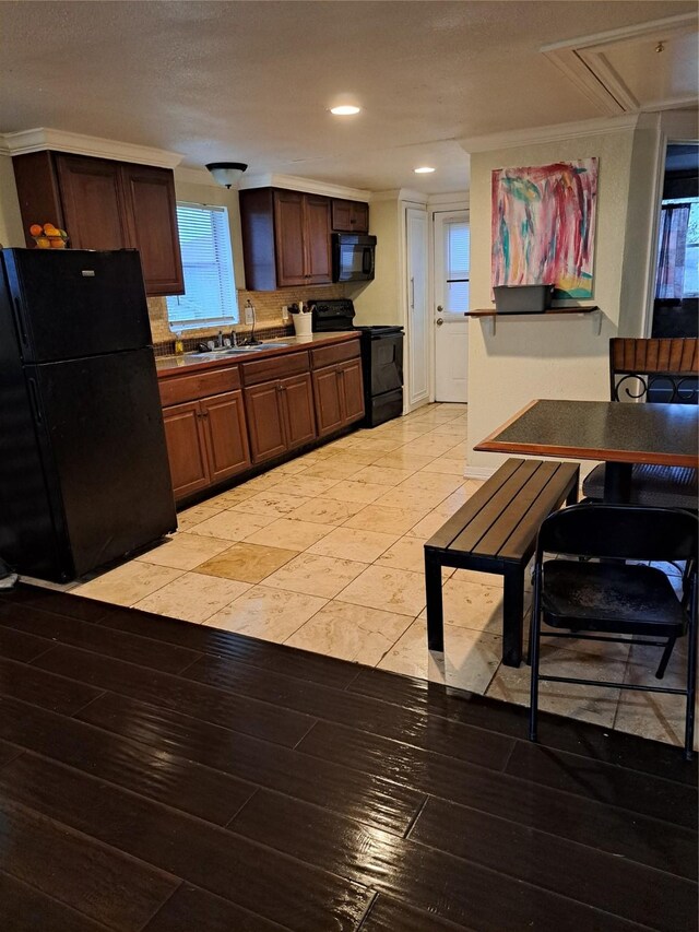 kitchen with sink, crown molding, black appliances, and light hardwood / wood-style floors