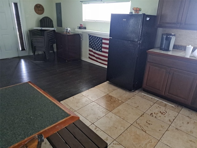 kitchen with tasteful backsplash, black fridge, and light wood-type flooring