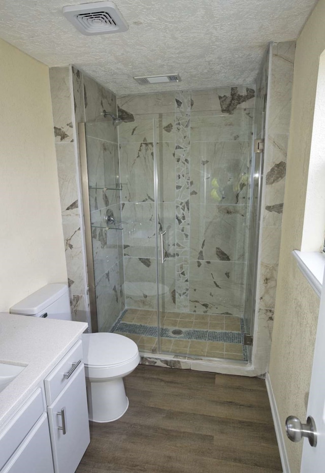 bathroom with toilet, a textured ceiling, an enclosed shower, hardwood / wood-style floors, and vanity