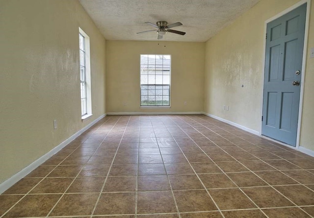 tiled empty room with a textured ceiling, ceiling fan, and a wealth of natural light