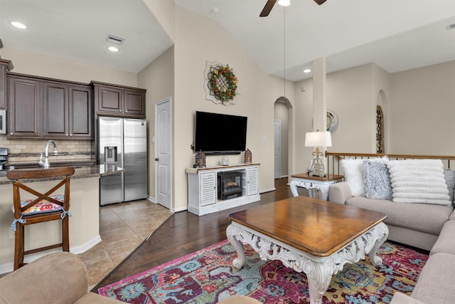 living room featuring light wood-type flooring, high vaulted ceiling, ceiling fan, and sink