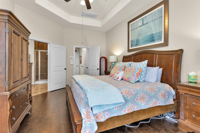 bedroom with a tray ceiling, ceiling fan, dark wood-type flooring, and a towering ceiling