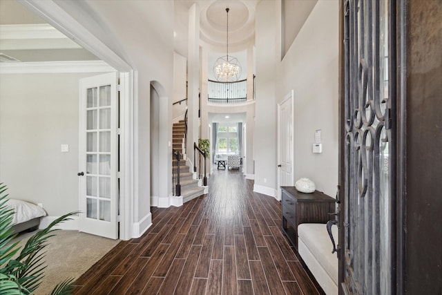 foyer with baseboards, arched walkways, stairs, wood finish floors, and a chandelier