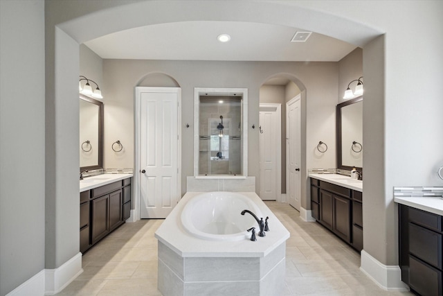 full bathroom featuring a garden tub, a sink, two vanities, and visible vents