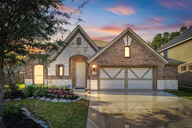 view of front facade featuring a garage, stone siding, brick siding, and driveway