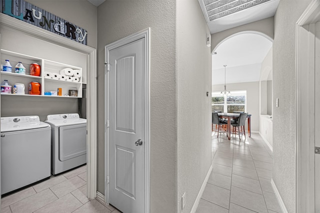 washroom featuring laundry area, arched walkways, washer and dryer, and light tile patterned flooring